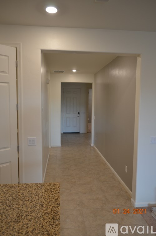 A hallway with a carpeted floor and white walls.