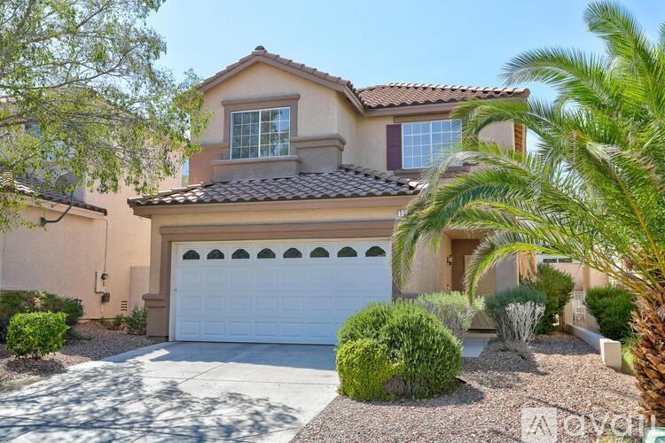 A house with a white garage door and a palm tree in front.