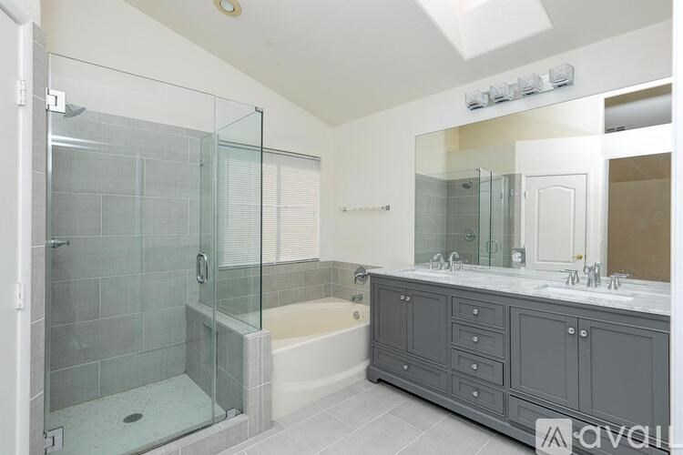A modern bathroom with a glass shower enclosure and a white bathtub.