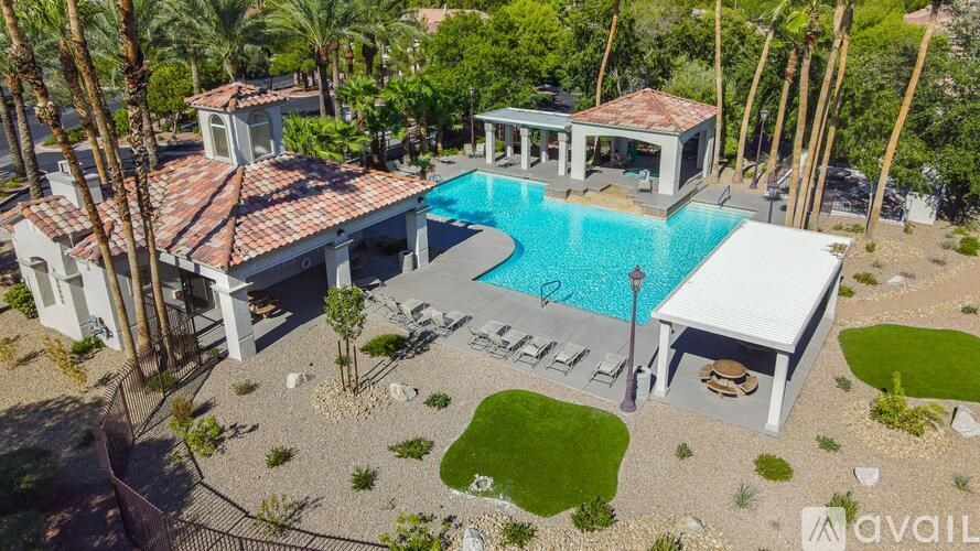 A large house with a pool and a hot tub surrounded by palm trees.