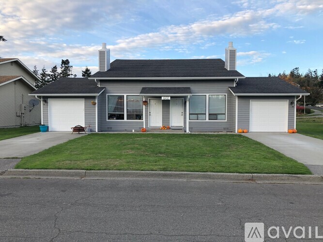 A house with a grey roof and white walls is for sale.