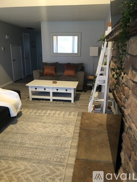 A living room with a white coffee table and a stone wall.