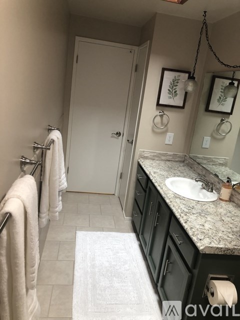 A bathroom with a sink, mirror, and towel rack.