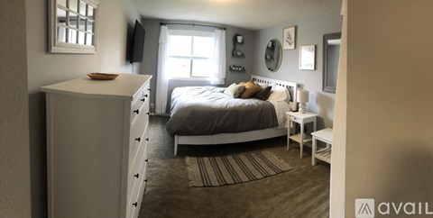 A bedroom with a bed, nightstand, and window.