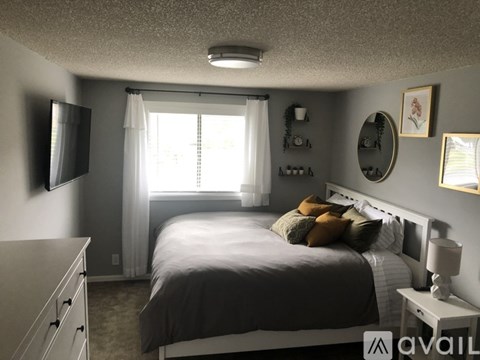 A bedroom with a bed, nightstand, and a window with curtains.