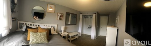 A bedroom with a bed, nightstand, and a mirror on the wall.