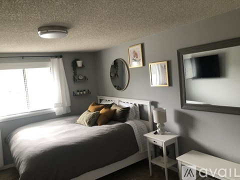 A bedroom with a bed, nightstand, and a mirror on the wall.