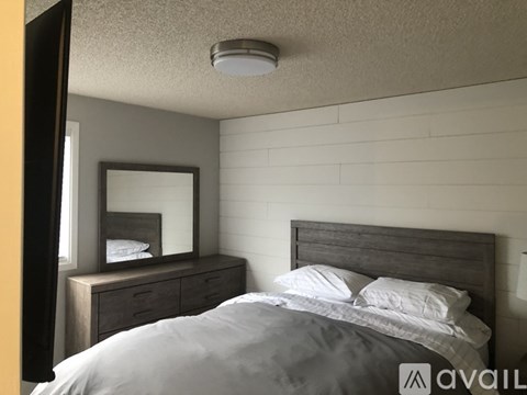 A bedroom with a bed, nightstand, and mirror.