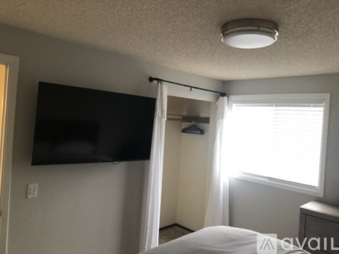 A bedroom with a bed, a television, and a window with curtains.