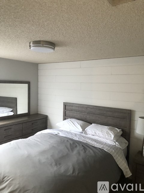 A bedroom with a bed, nightstand, and a mirror.