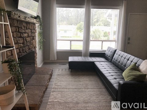 A living room with a black couch and a stone fireplace.