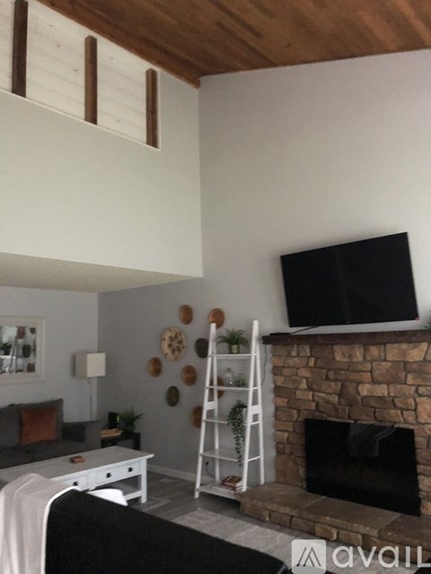 A living room with a fireplace and a television mounted above it.