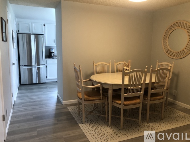 A kitchen with a refrigerator and a dining table with chairs.