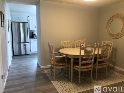 A kitchen with a refrigerator and a dining table with chairs.