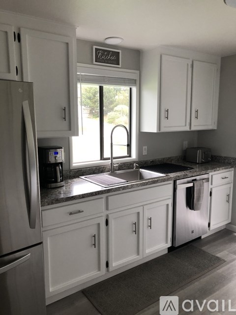 A kitchen with white cabinets and a refrigerator.