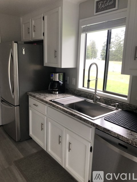 A kitchen with a fridge, cabinets, and a window.