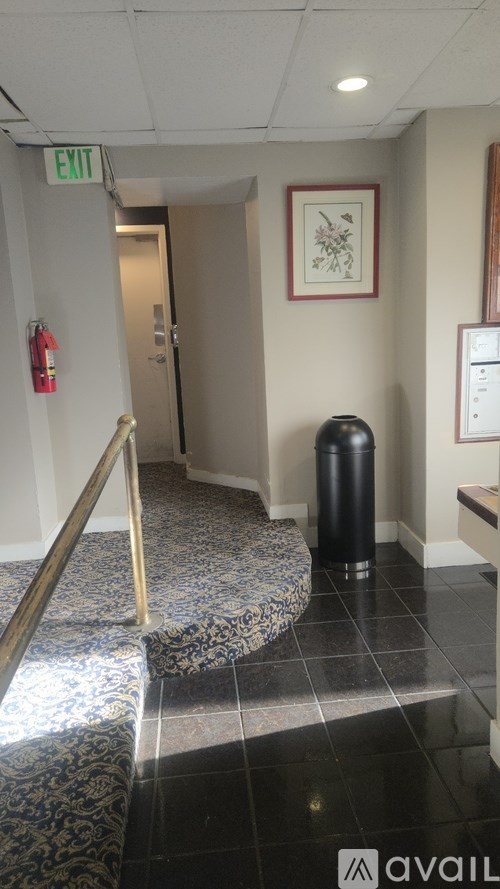 A hallway with a fire extinguisher on the wall and a trash can on the floor.