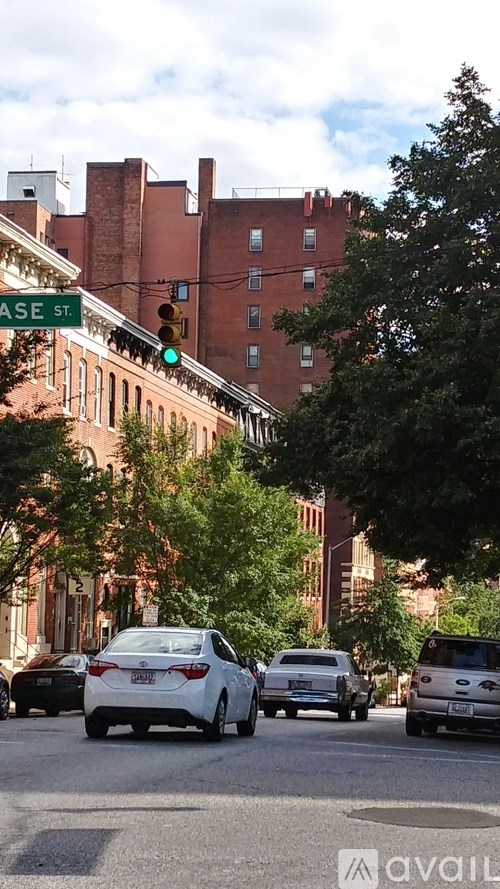 A white car is stopped at a green light on a city street.