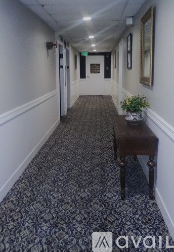 A long hallway with a patterned carpet and a bench.