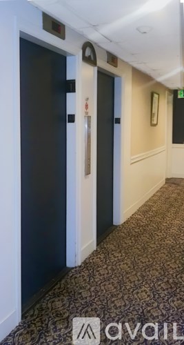 A hallway with a carpeted floor and a wall-mounted light fixture.