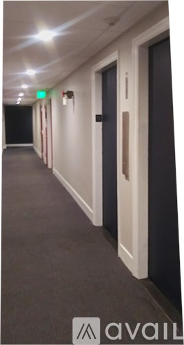 A long hallway with doors on both sides and a green light on the wall.