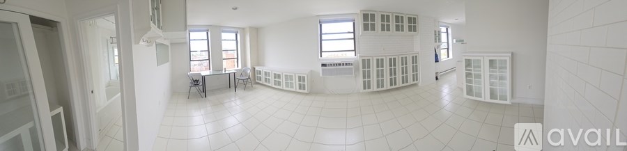 A white tiled room with a table and chairs.