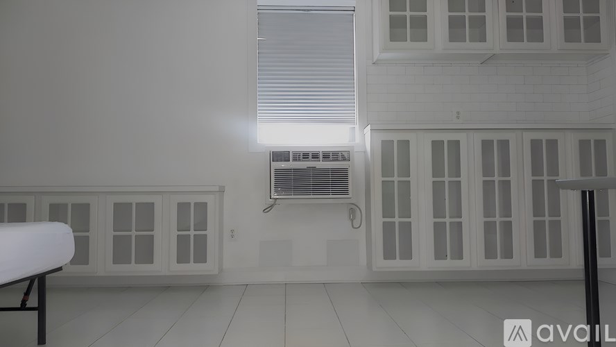 A room with a window, a wall-mounted air conditioner, and a white table.