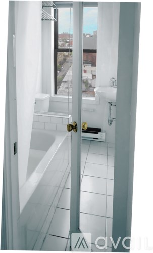 A bathroom with a tub and a window overlooking a city.