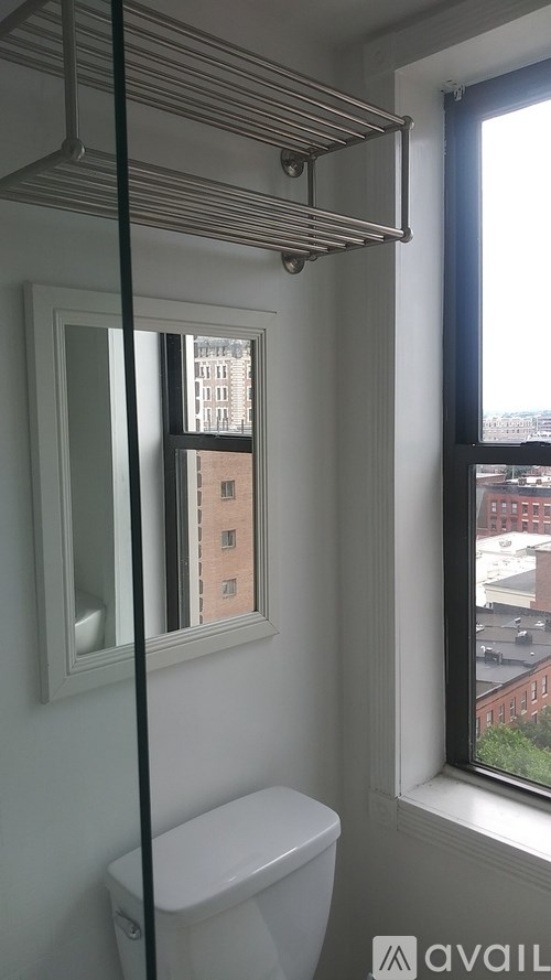 A bathroom with a toilet, a mirror, and a window.