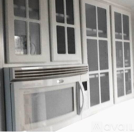 A white cabinet with glass doors and a microwave oven.