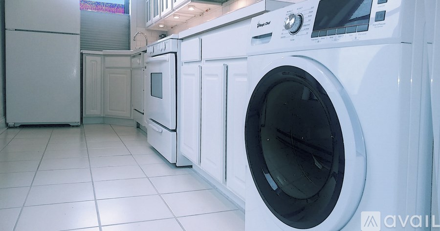 A row of white front loading washing machines in a laundromat.