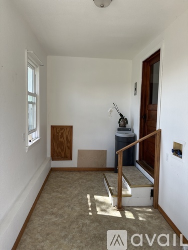 A room with a window, a door, and a staircase leading to another room.