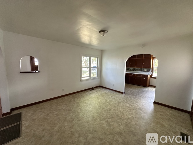A spacious room with a window and a door leading to another room.