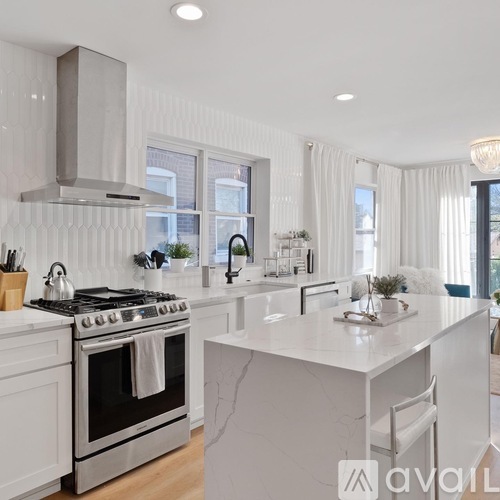 A modern kitchen with a white marble countertop and stainless steel appliances.