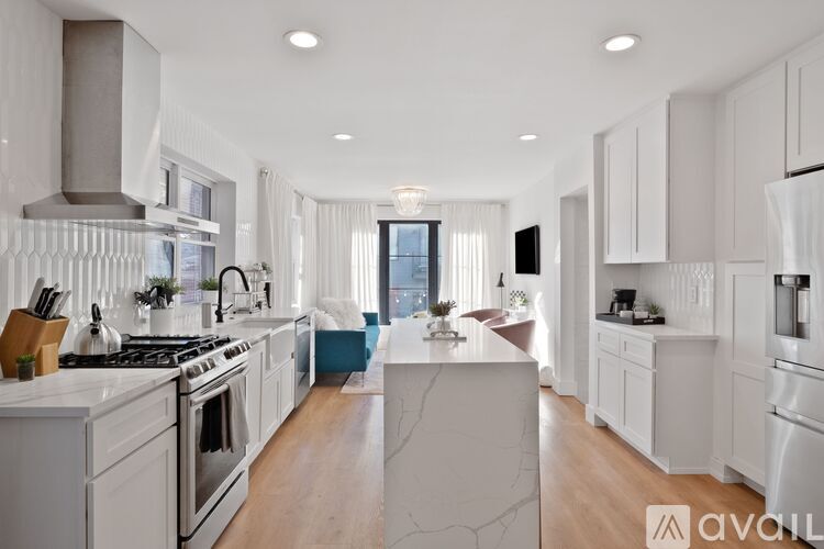 A modern kitchen with white cabinets and a marble island.