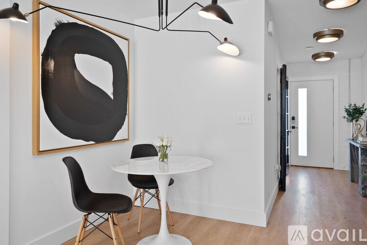 A modern dining room with a white table and black chairs.