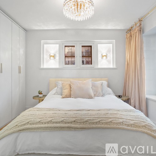 A bedroom with a large bed and a chandelier.