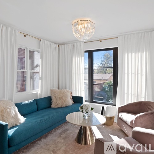 A living room with a blue couch, a white coffee table, and a chandelier.