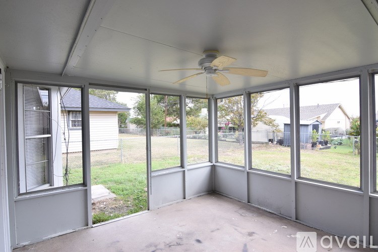 A sunroom with a ceiling fan and sliding glass doors.