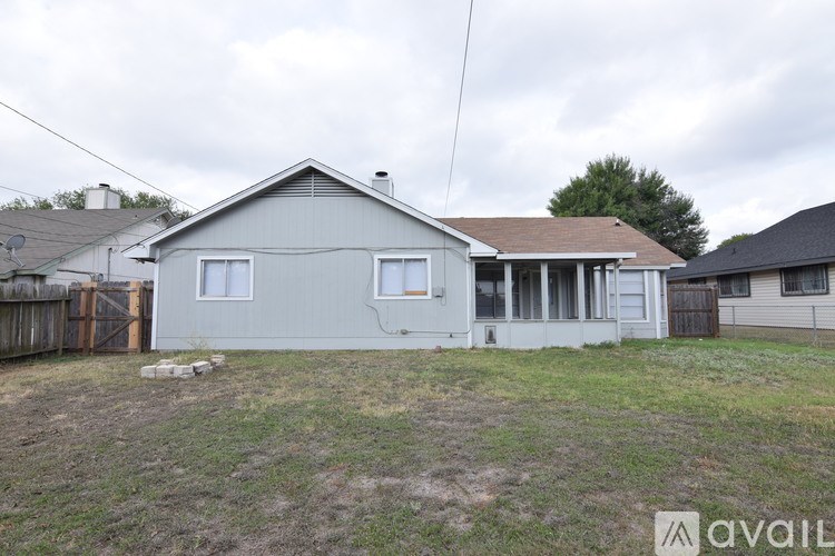 A house with a grey roof and a white fence is available for rent.