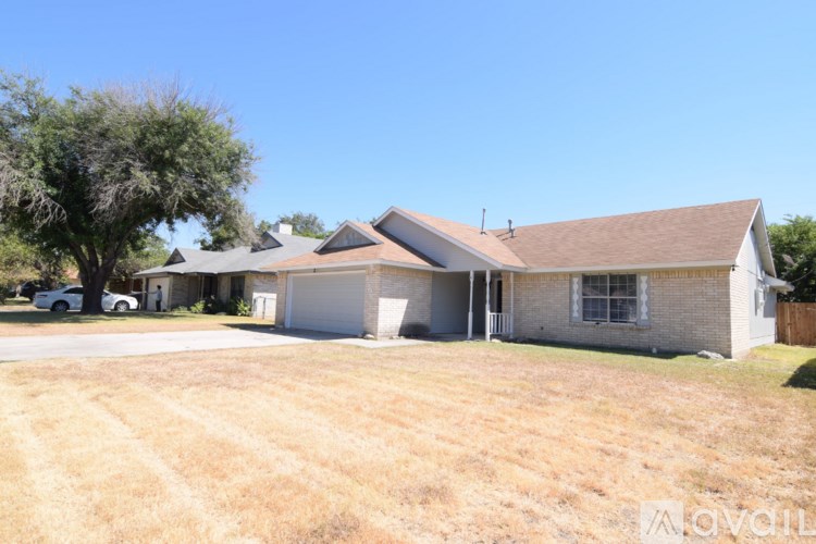 A house with a garage and a tree in front of it.