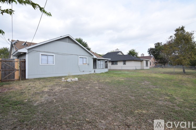 A grey house with a brown fence and a tree in front.