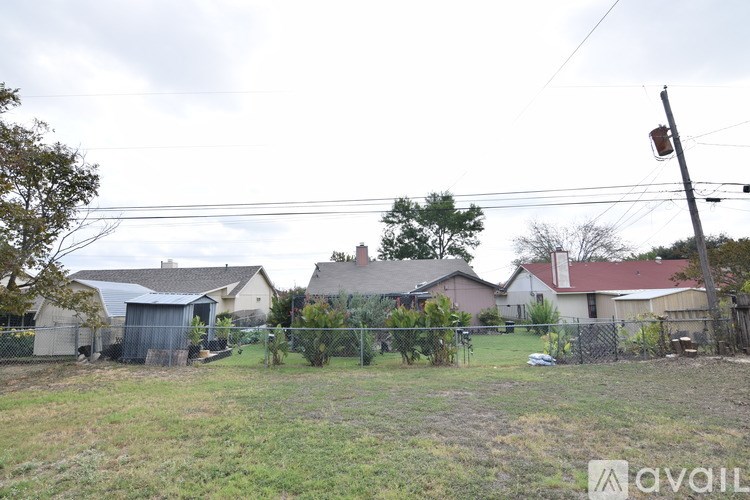 A grassy field with a house and trees in the background.