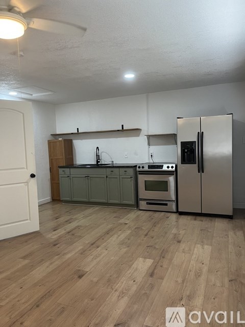 A kitchen with a refrigerator, oven, and sink.