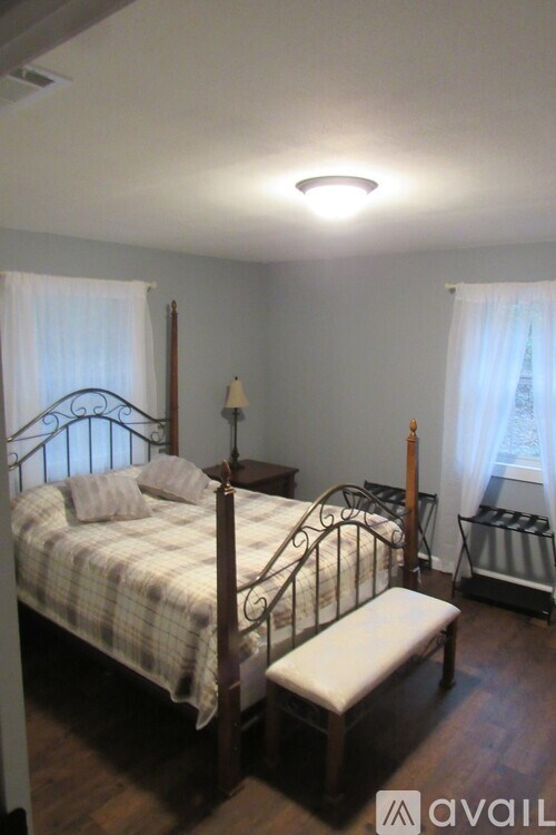 A bedroom with a bed, bench, and window.