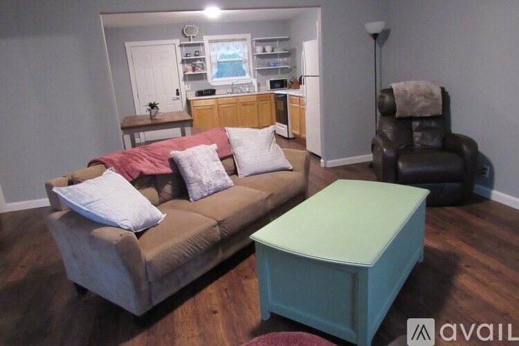 A living room with a brown couch and a green ottoman.