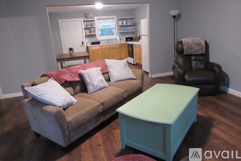 A living room with a brown couch and a green ottoman.