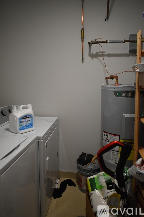 A room with a washing machine, a water heater, and a ladder.