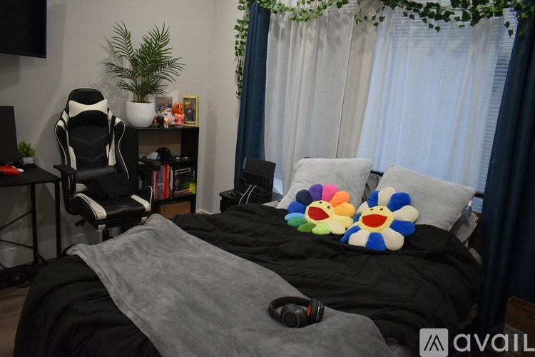A bedroom with a bed, a chair, a plant, and a window with curtains.