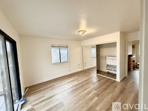 A room with wooden flooring and a window with blinds.